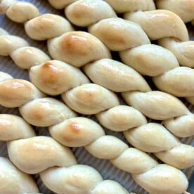 Twisted sourdough discard breadsticks on a baking sheet.