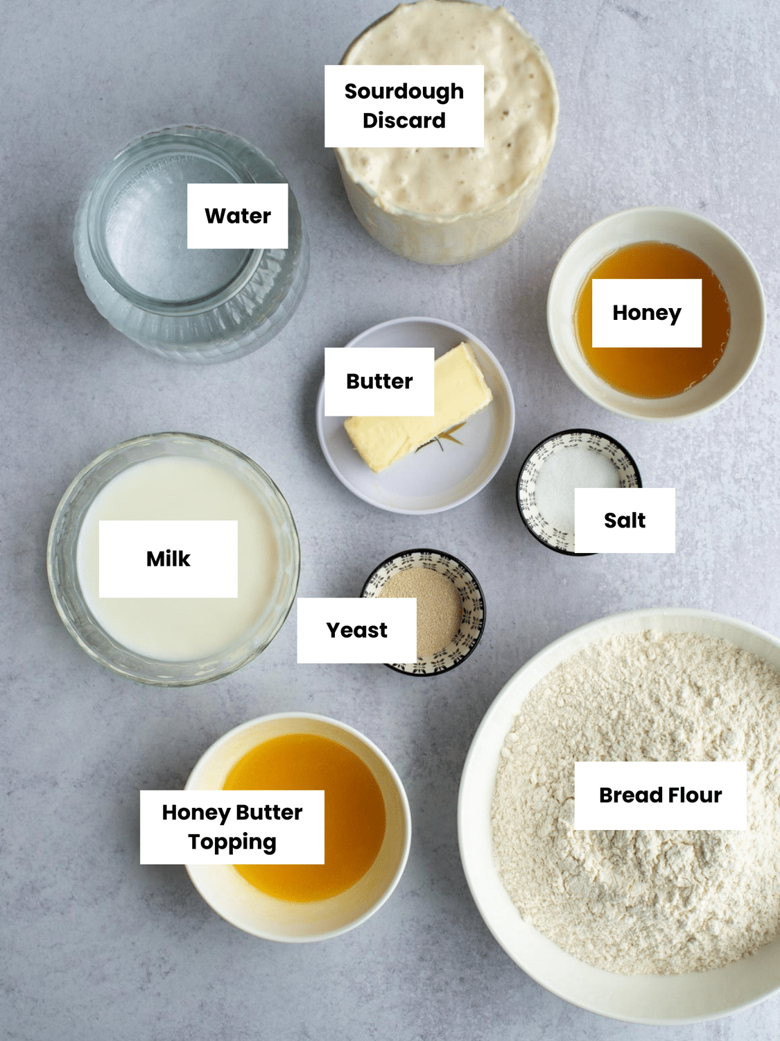 Ingredients for honey butter sourdough discard rolls labeled on a countertop.