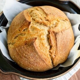 Sourdough spelt loaf in a dutch oven on a piece of parchment paper.