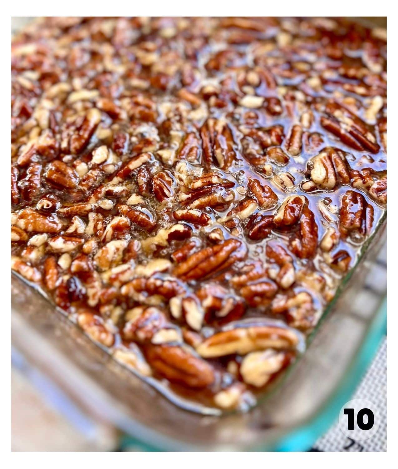 A glass dish contains a sticky pecan mixture.