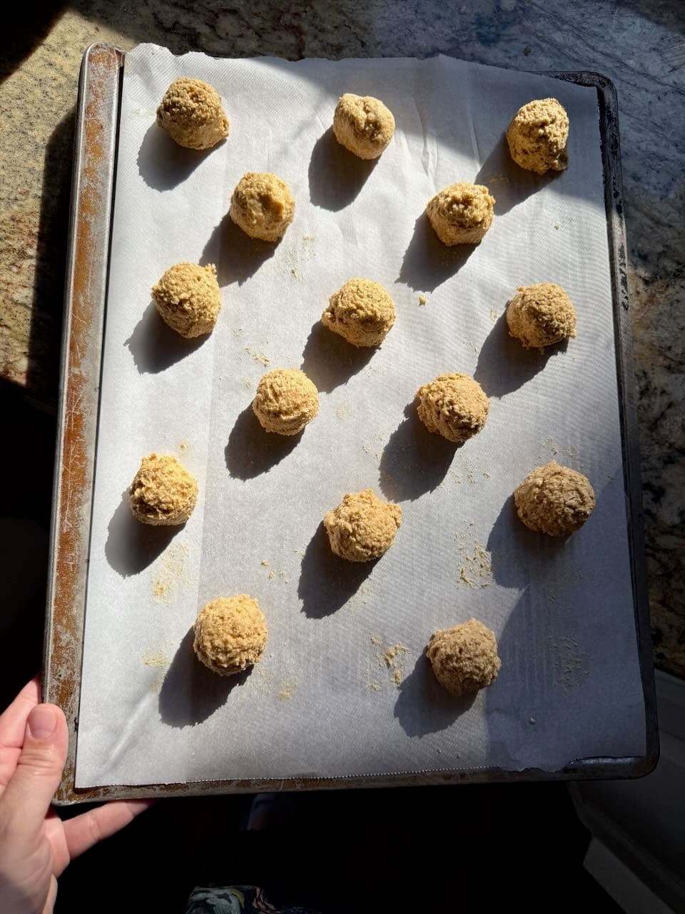 Scooped cookie dough balls arranged evenly on a parchment-lined baking sheet, ready for baking.