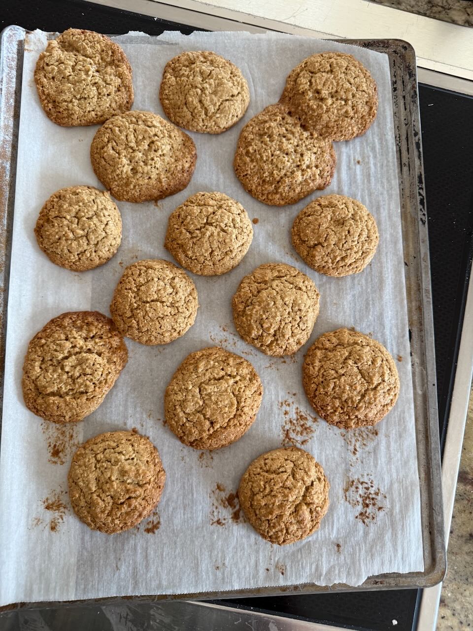 Baked cookies sit on a parchment lined baking sheet.