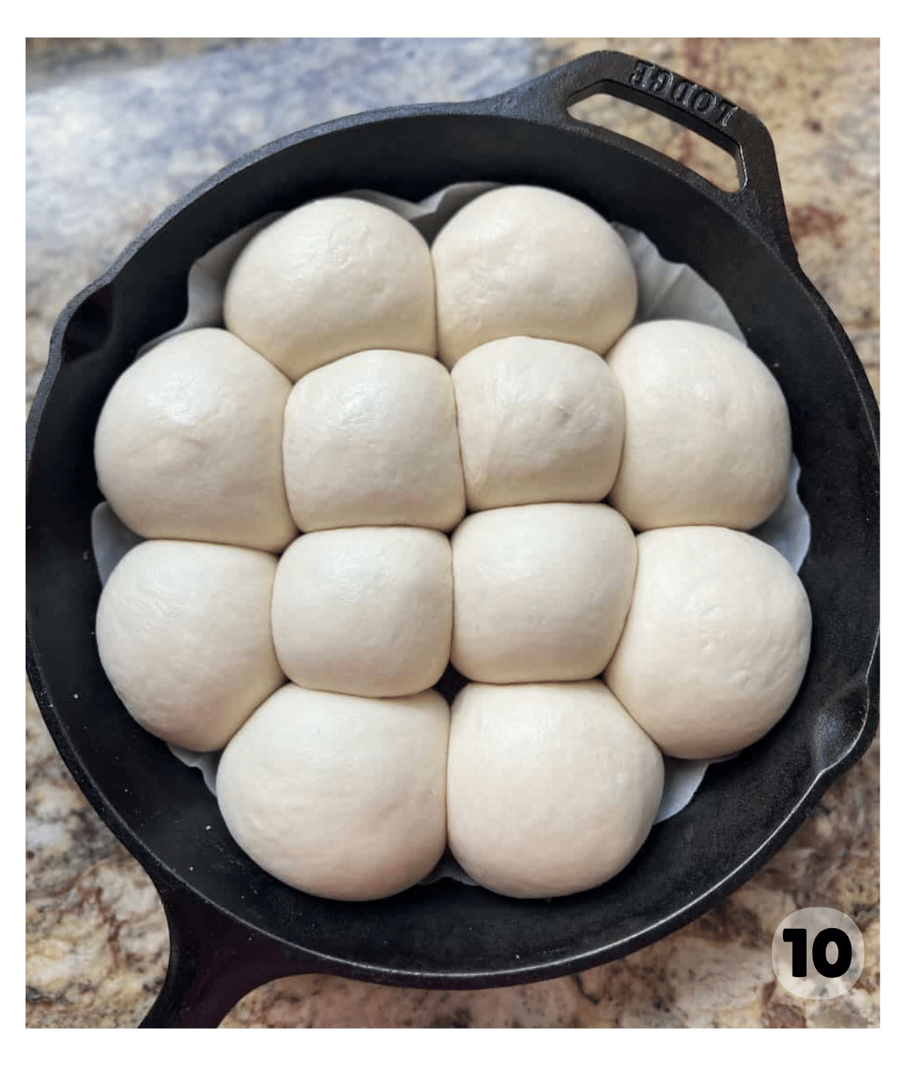 Shaped dough balls arranged snugly in a cast iron skillet lined with parchment paper are puffed and risen before proofing.