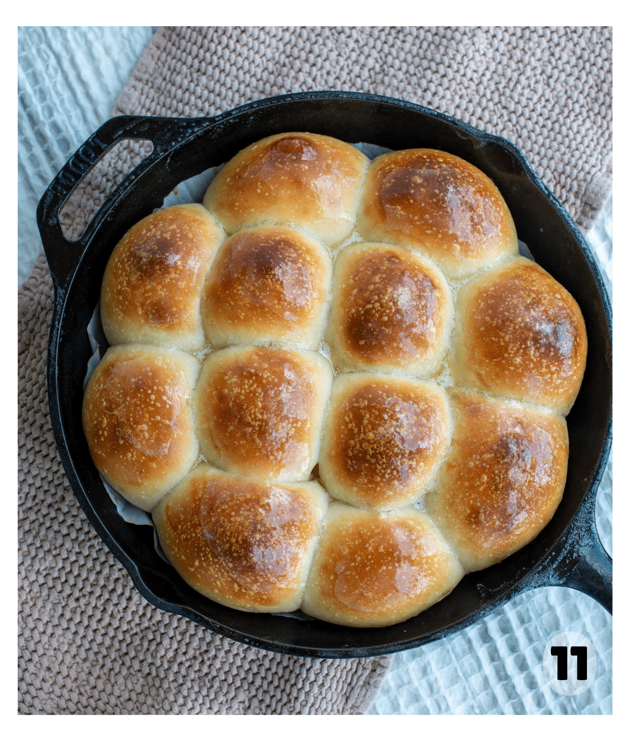 Baked sourdough potato rolls in a cast iron skillet, golden brown on top and ready to serve.