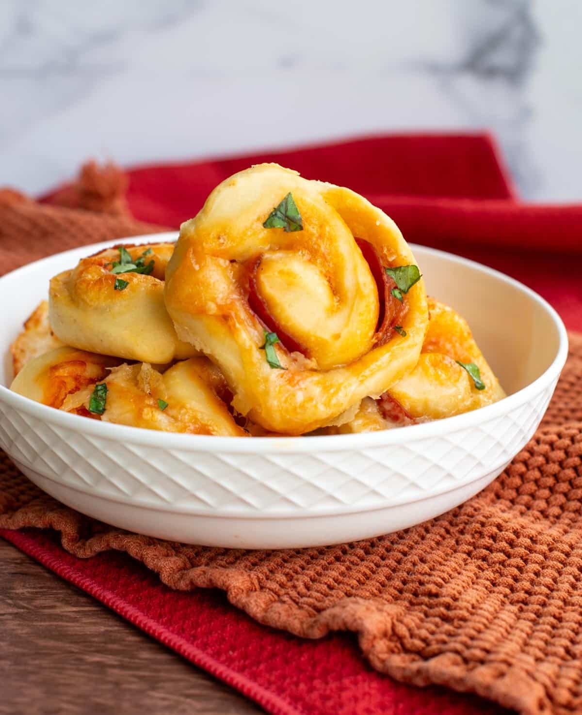 A white bowl contains sourdough pizza rolls with cheese, sauce, and pepperoni visible.
