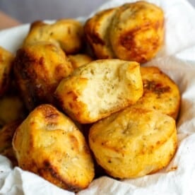 Sourdough focaccia rolls in a bowl with a bite taken out of one of them.