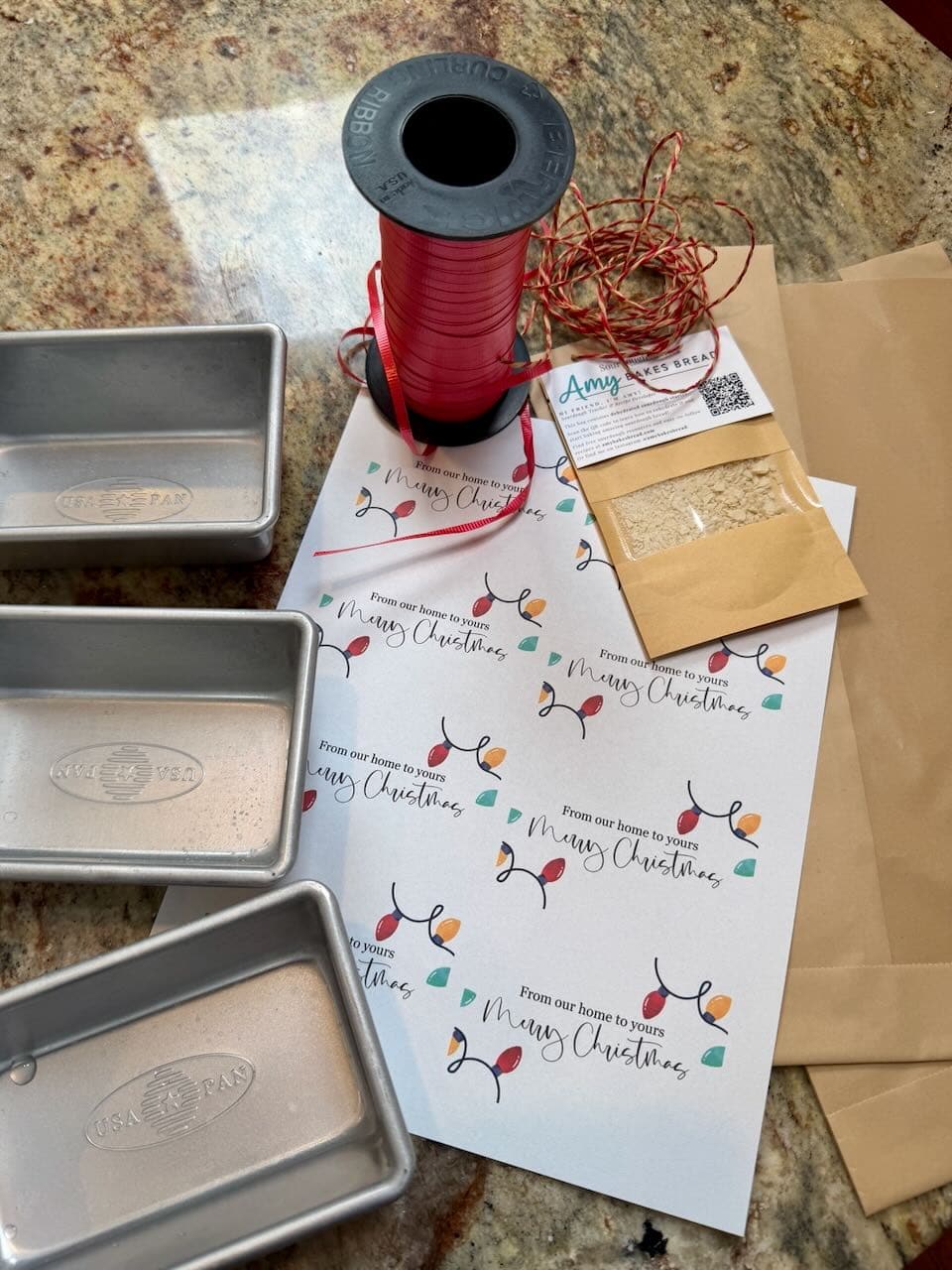 Mini loaf pans, twine, paper bags, and holiday labels sit on a kitchen counter.