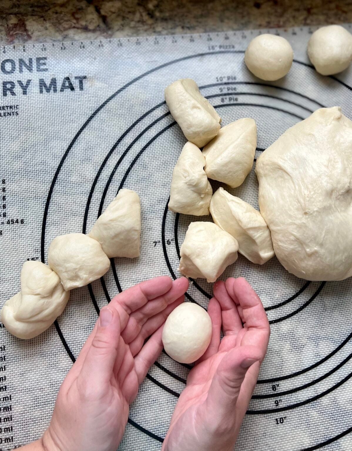 Hands shape small piece of dough into round balls.