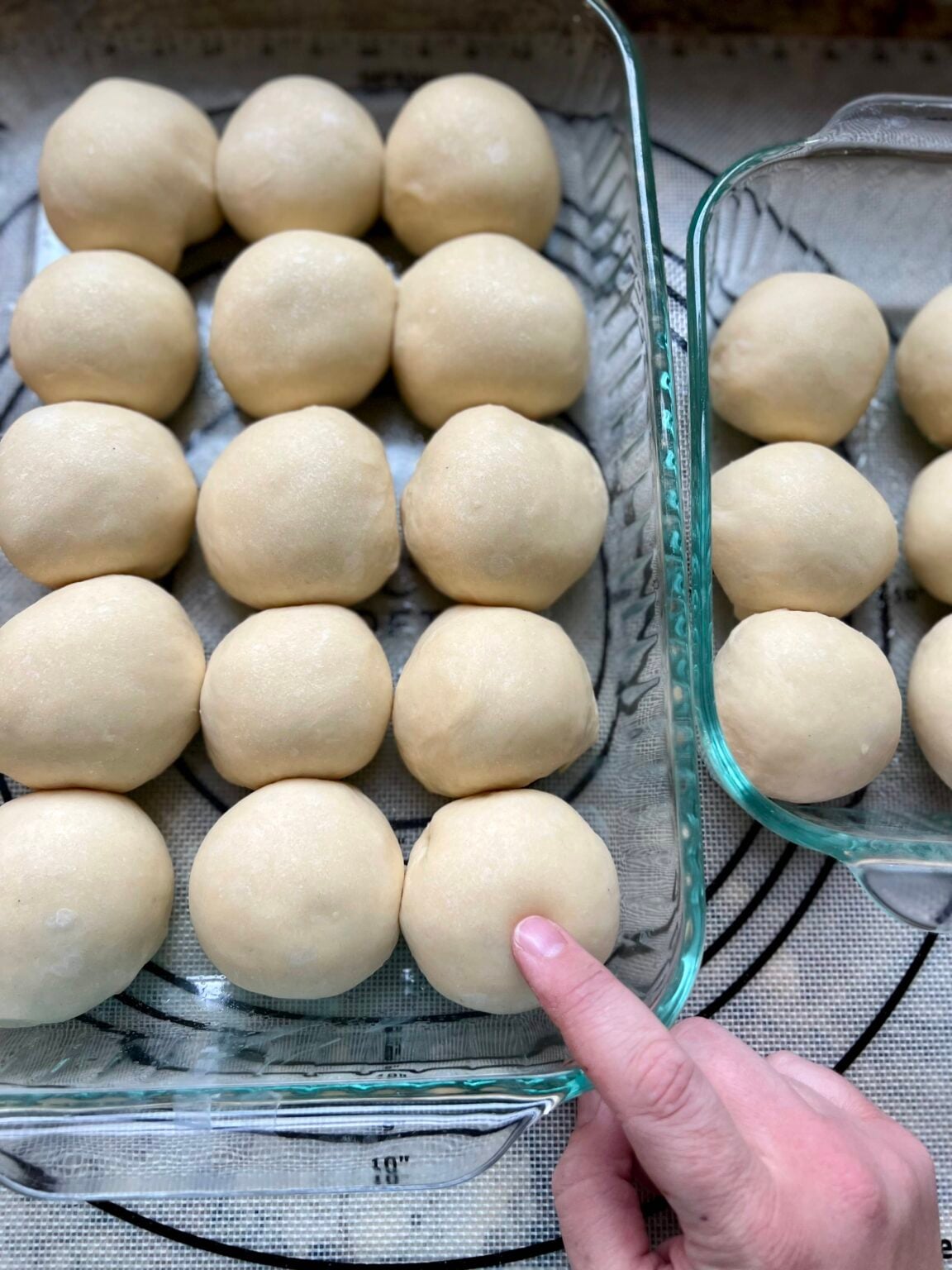A finger presses into proofed rolls, testing for readiness to bake.