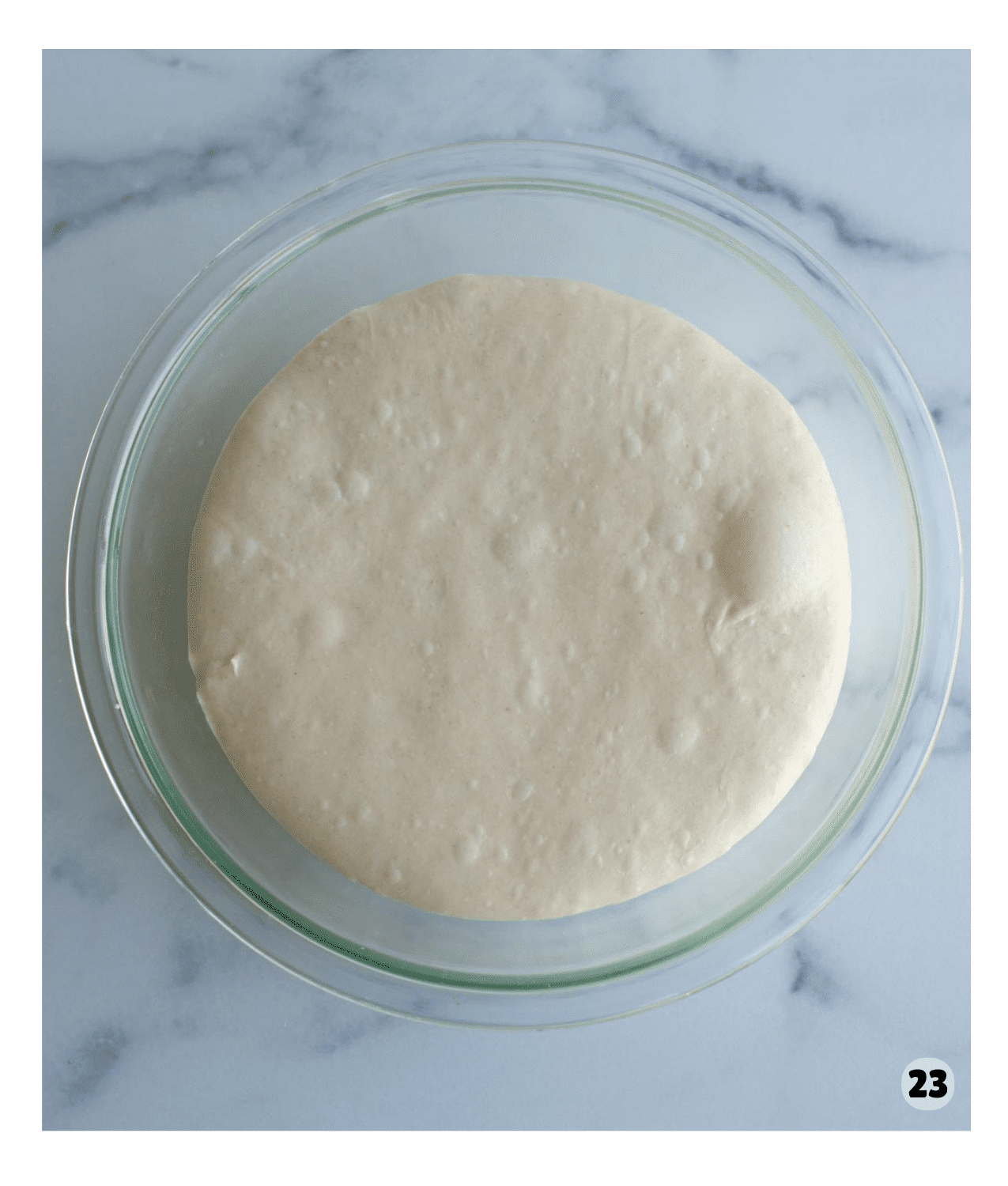 A bowl of dough is puffed with bubbles on the surface.