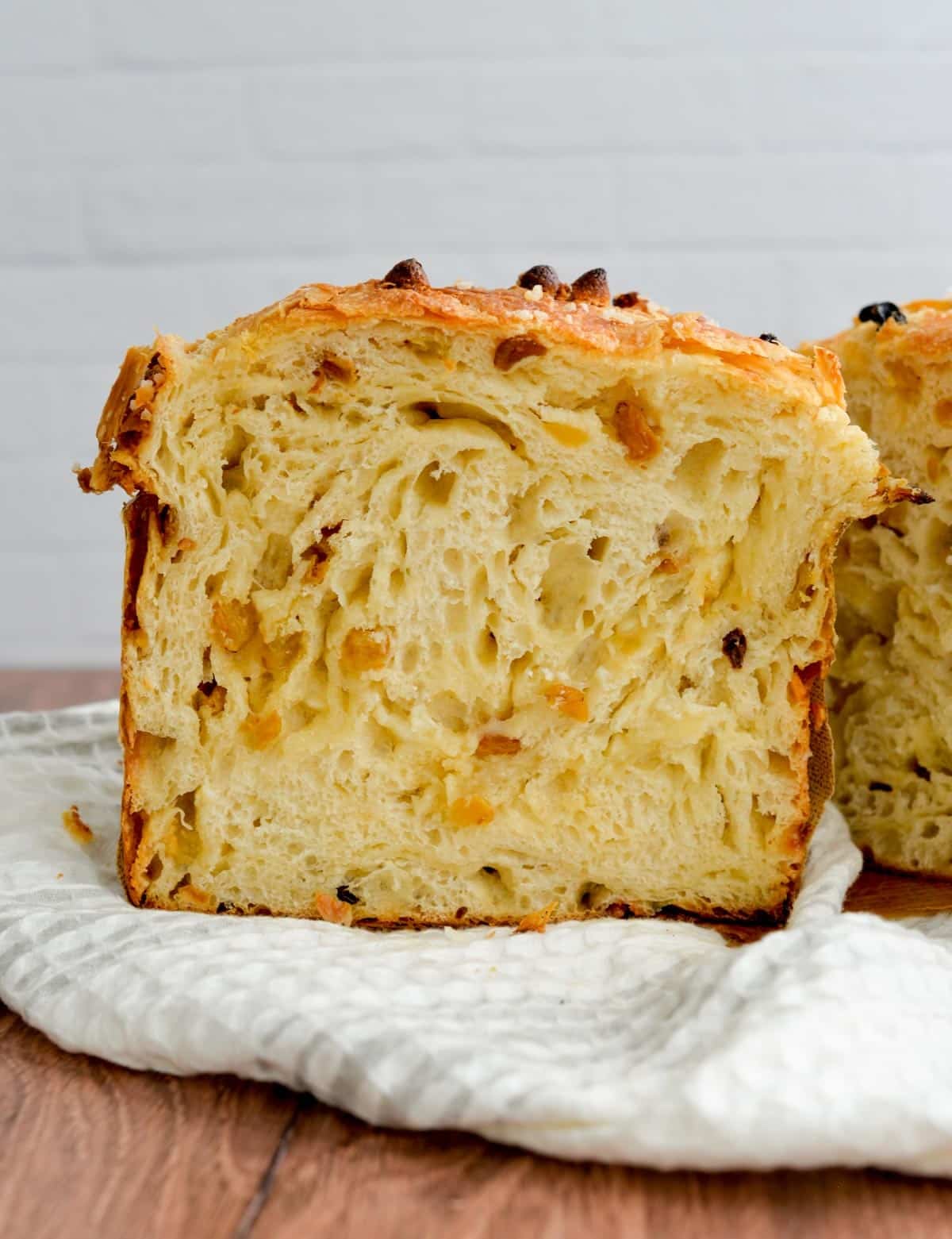A sliced open half of panettone sourdough bread has buttery and flaky layers with candied fruits.