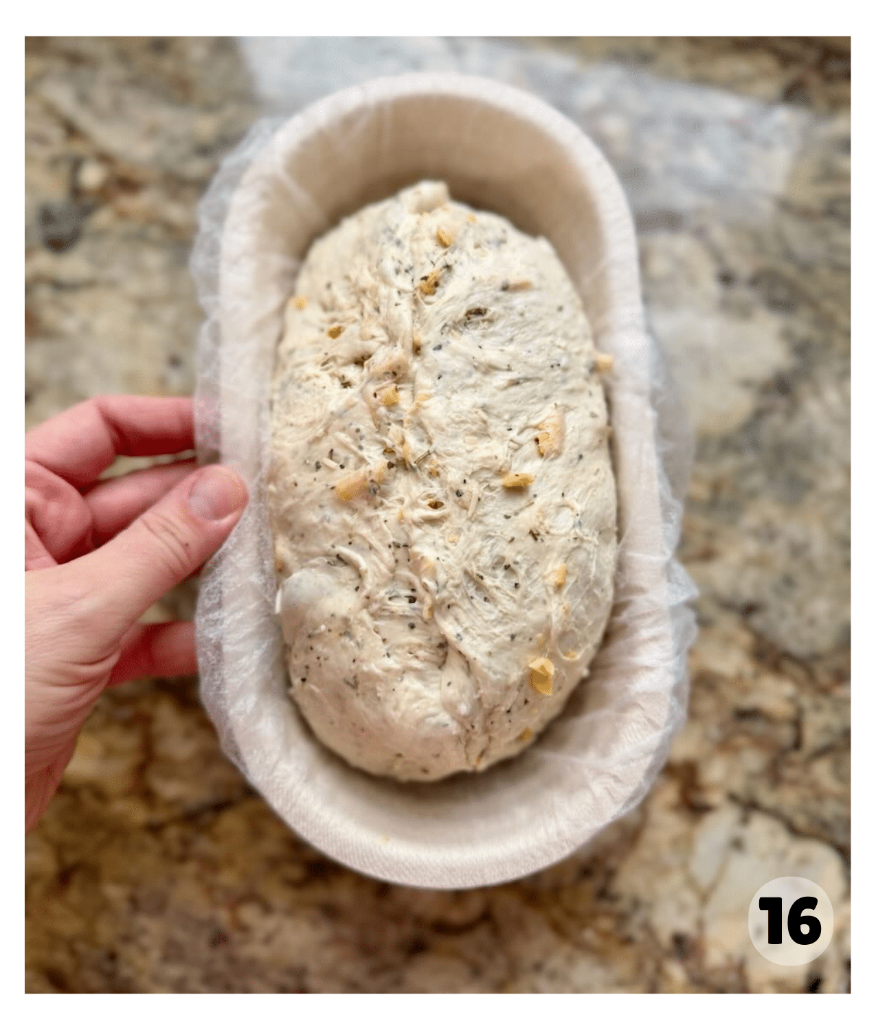 A puffed and jiggly oval shaped sourdough batard sits in a banneton basket.