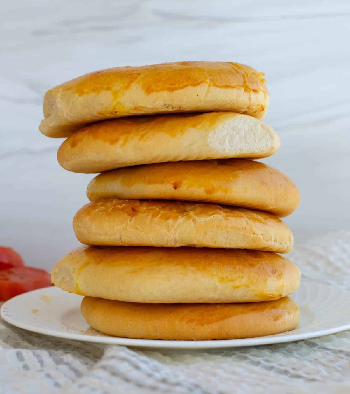 A stack of six doener kebab bread rolls sit stacked on a white plate.