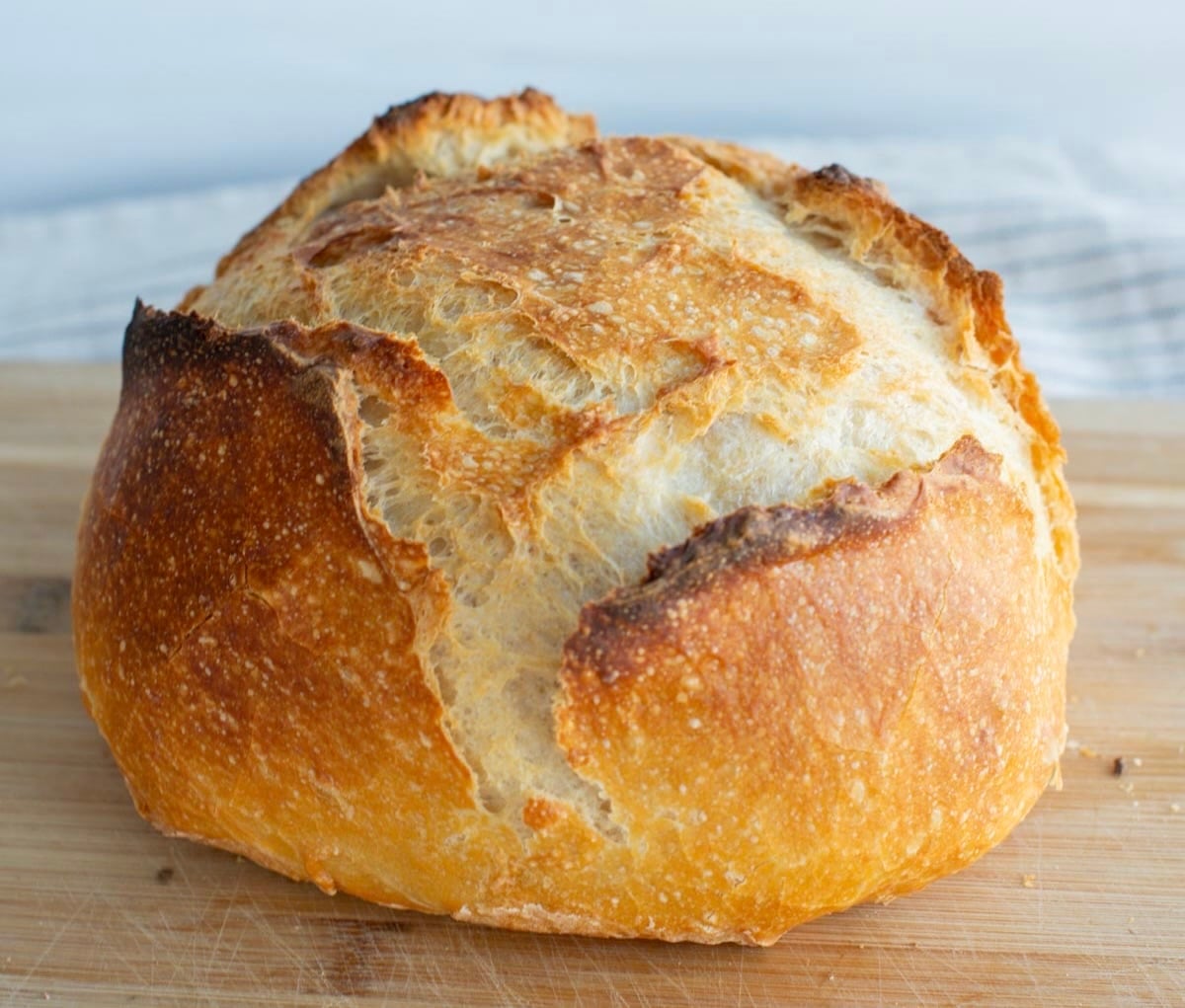 A crusty loaf of sourdough discard bread sits on a cutting board.