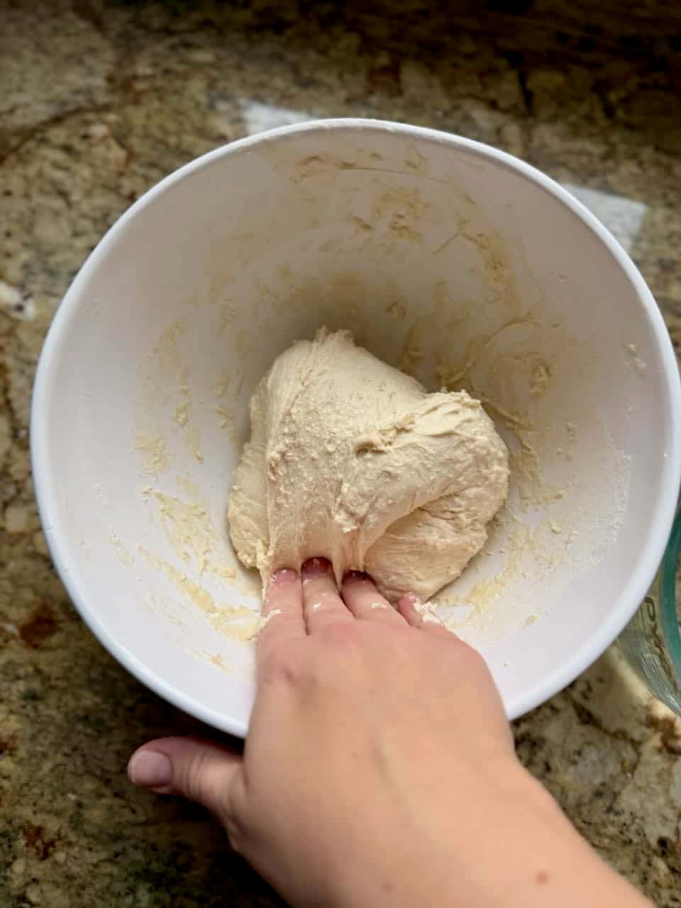 A hand folds dough over onto itself.