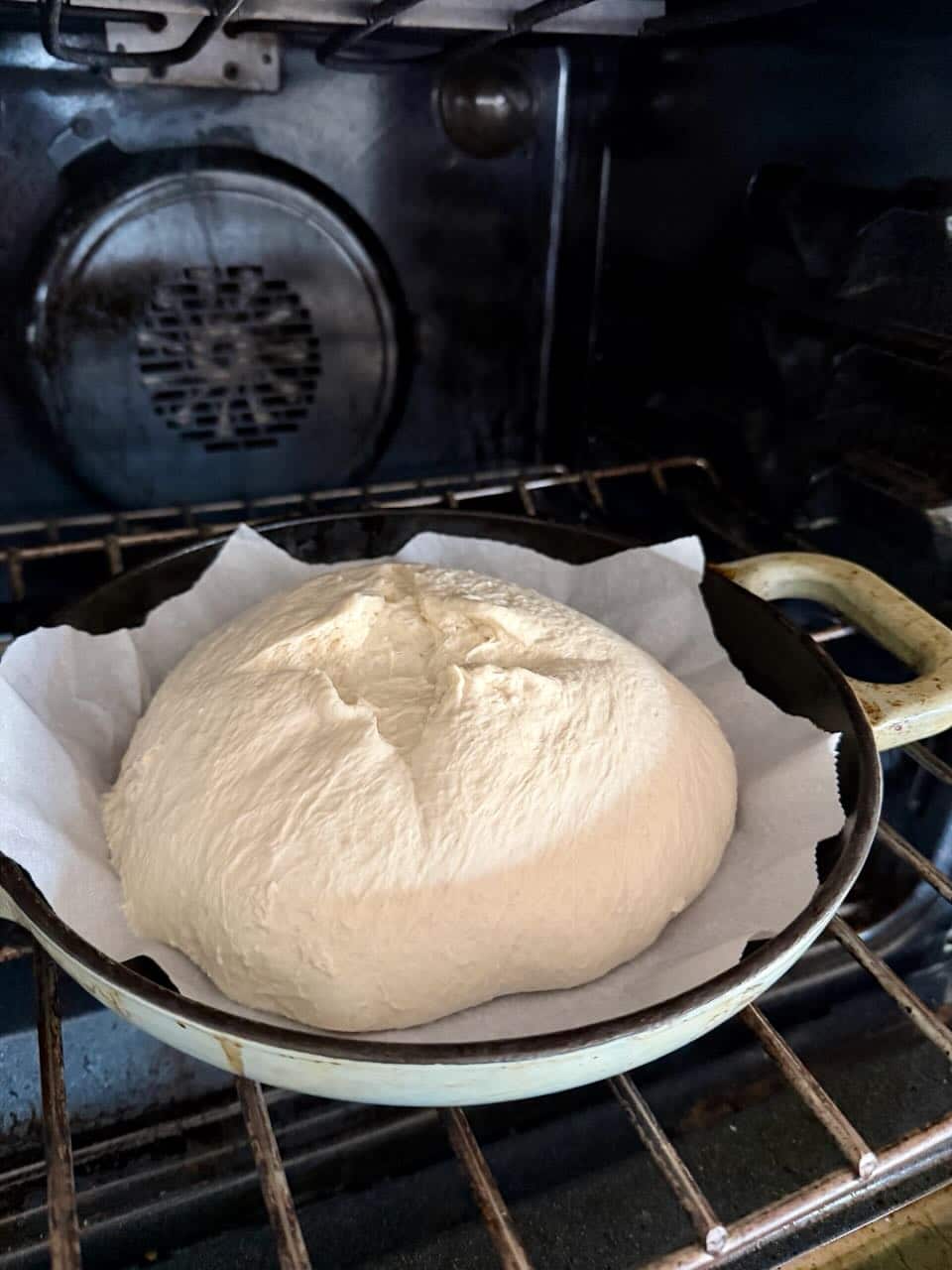 Dough sitting in a Dutch oven bakes in an oven.