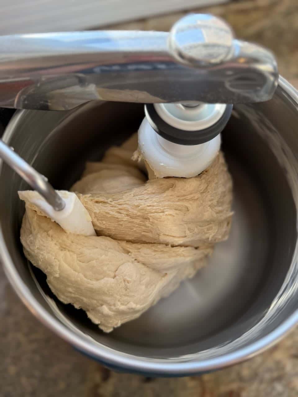 Dough turns in a stand mixer on a dough hook.