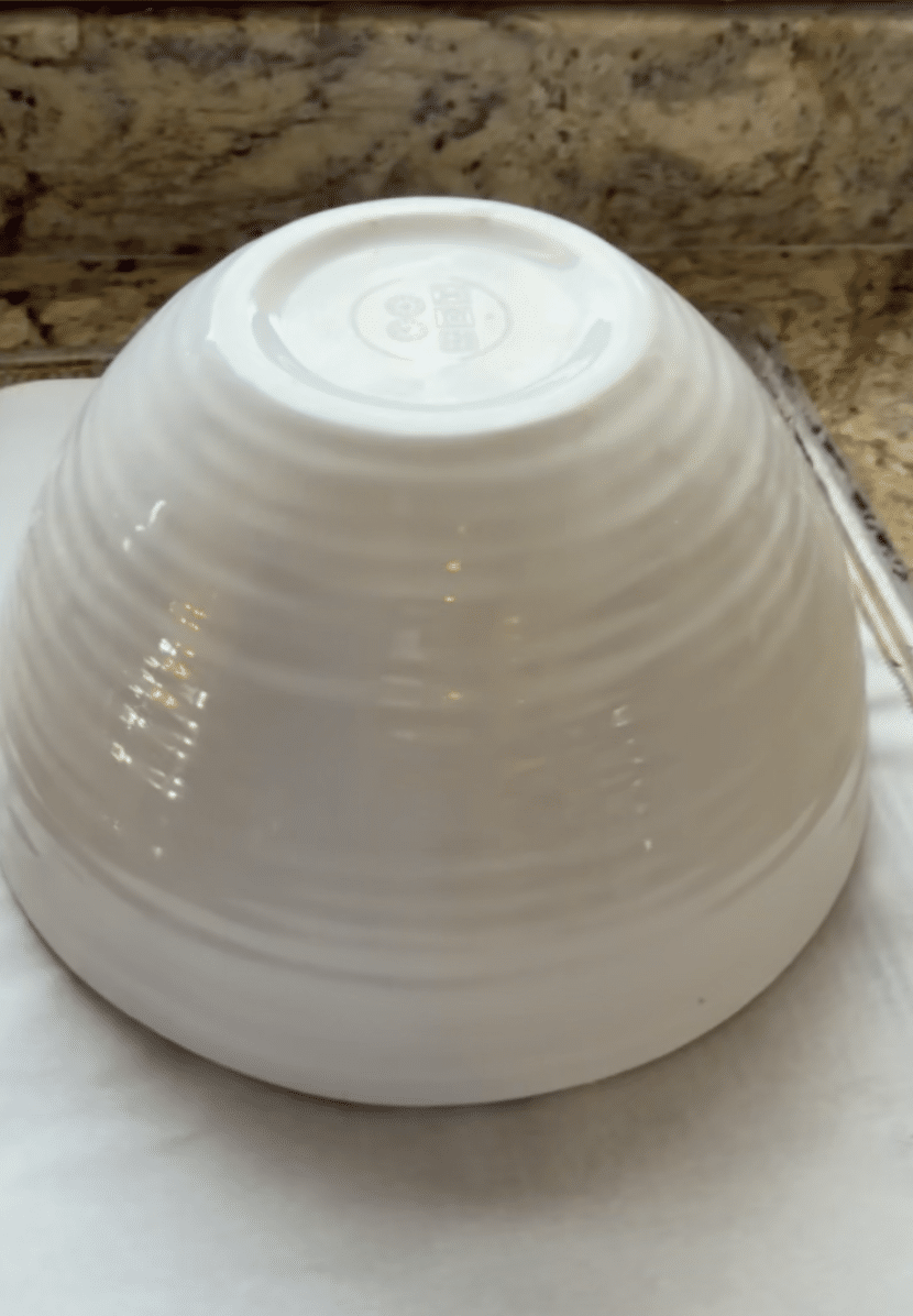 Bowl covering a round of dough.