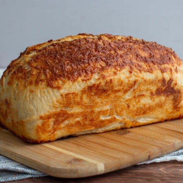 Sourdough Asiago Bagel bread loaf on a cutting board.