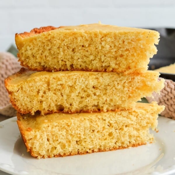 A plate of three pieces of sourdough discard cornbread stacked on top of each other.