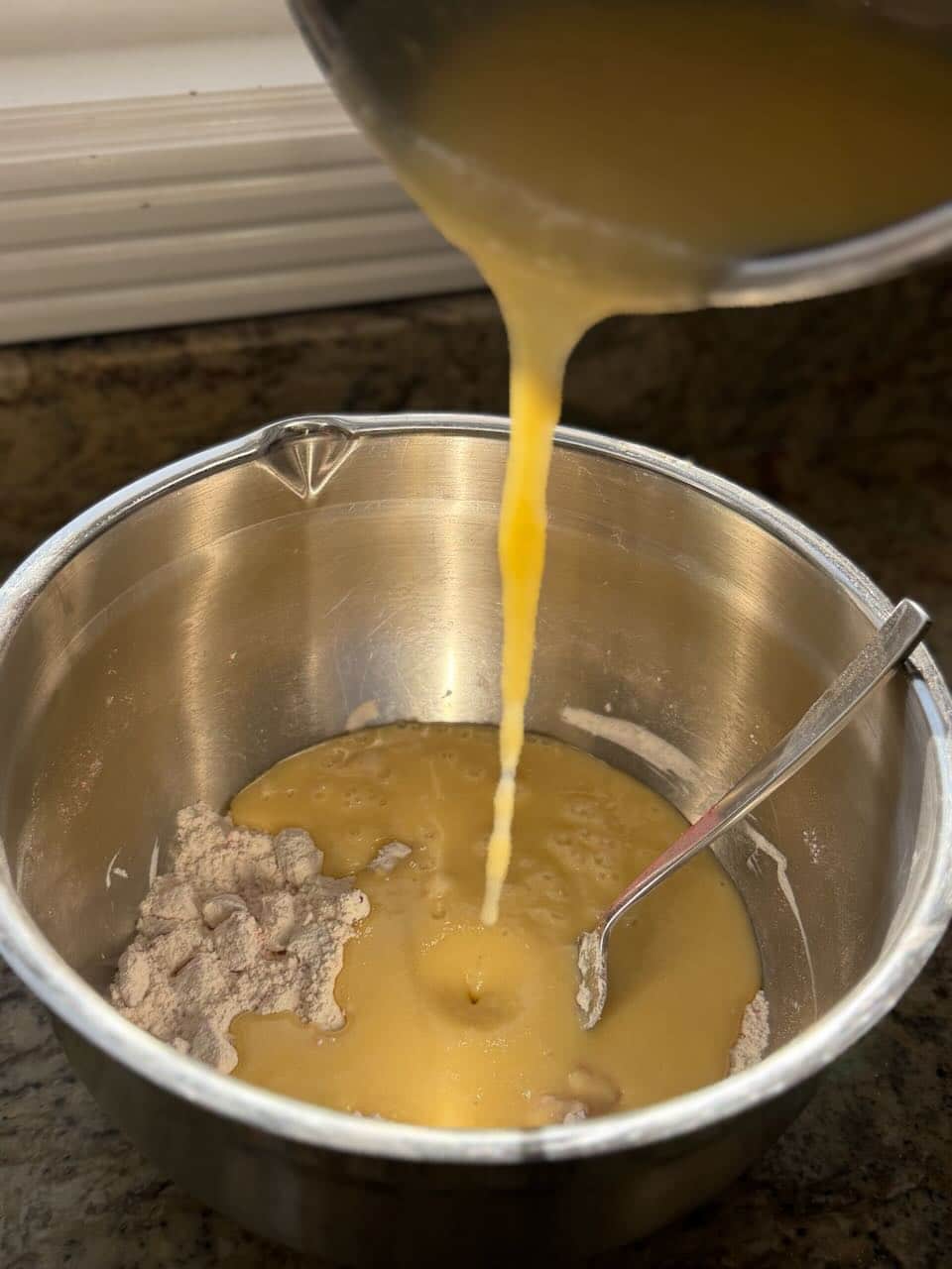 The wet mixture is poured into the bowl of dry ingredients to combine into the batter.