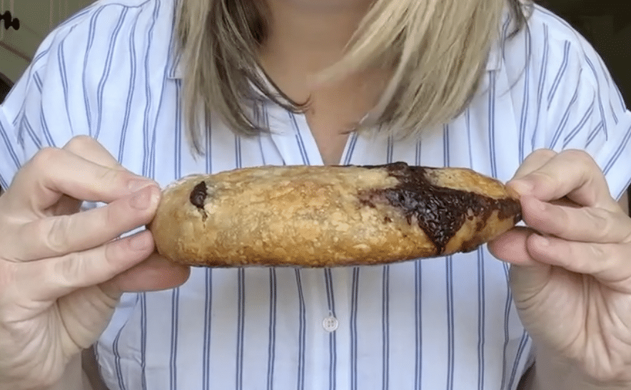 Flat loaf of sourdough bread being held between two hands.